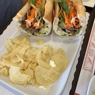 two sub sandwiches and chips on a plate
