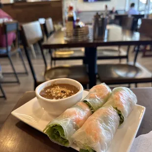 a plate of spring rolls and a bowl of dipping sauce