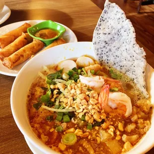 Turmeric Noodle Soup with Crispy Rolls in the background.