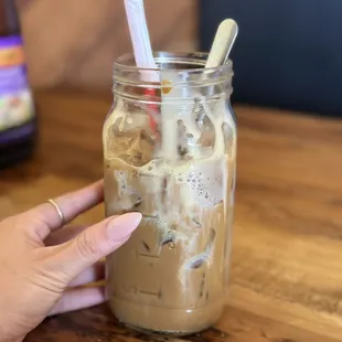 a hand holding a jar of iced coffee