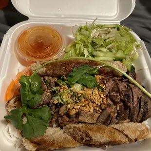 a styrofoam take out container with meat and vegetables