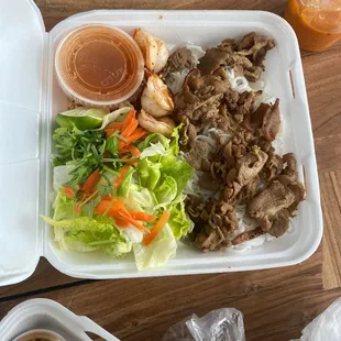 a tray of food with meat, lettuce, carrots, and sauce