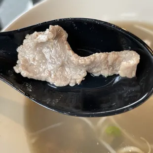 a spoon with a piece of meat in it