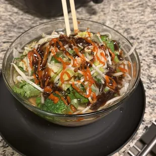 a bowl of stir fried vegetables with chopsticks