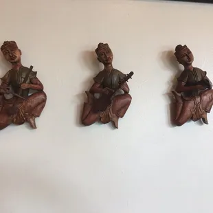 three wooden figurines on a wall