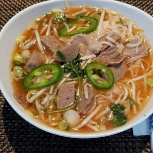 Pho&apos; regular size with medium rare round steak, extra meatballs.  Added sriratza, lime, jalapeno slices, sprouts, green onion, good broth.