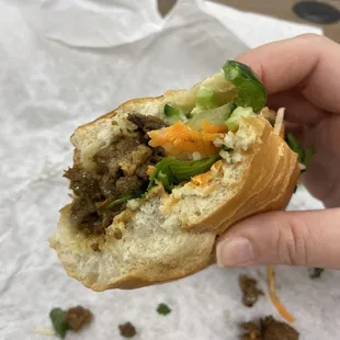 a hand holding a half eaten sandwich