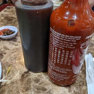 Hoisin sauce (dark bottle) &amp; Sriracha hot sauce (red bottle).