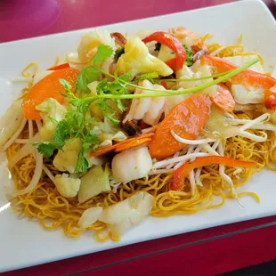 a plate of noodles with shrimp and vegetables