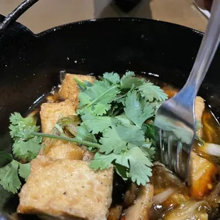 tofu and vegetables in a black bowl