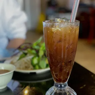 a glass of iced tea with a straw and a spoon