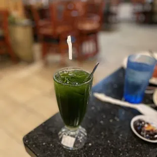 a glass of green juice on a table