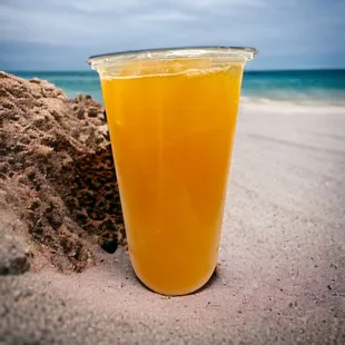 a glass of orange juice on the beach