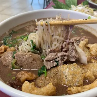 a bowl of soup with chopsticks