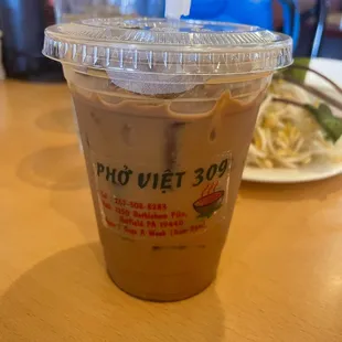 a plastic cup of iced coffee on a table