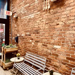 a bench and tables in front of a brick wall