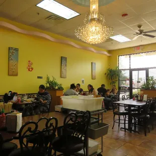 a dining area with tables, chairs, and a chandelier