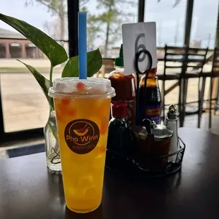 Passion fruit tea with bursting strawberry boba and the table sauces in background