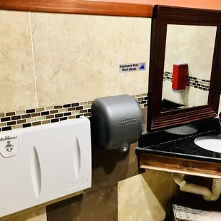 a bathroom with a sink, mirror and soap dispenser
