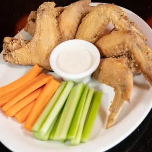 a plate of fried chicken wings, carrots, celery, and celery