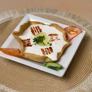 Labneh - Thick, creamy strained yogurt with garlic and mint, served with warm pita bread.