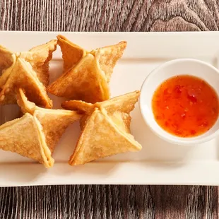 a plate of wontons with dipping sauce