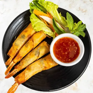 Crispy Shrimp Rolls-Freshly peeled shrimp marinated in house special seasoning and chopped basil, wrapped in wonton paper and fried
