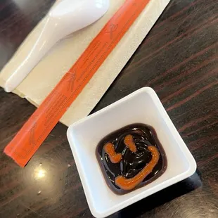 a spoon and a bowl of sauce on a table