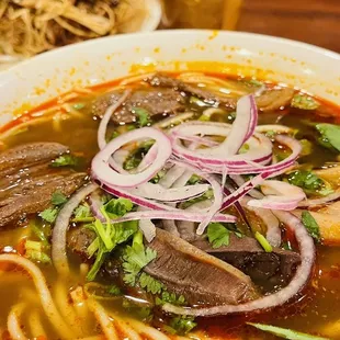 a bowl of soup with meat and onions