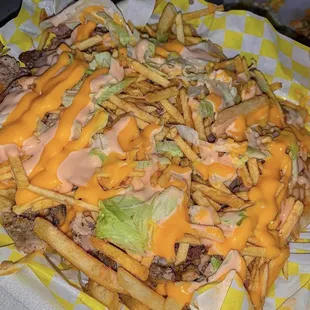 a plate of french fries with cheese and lettuce