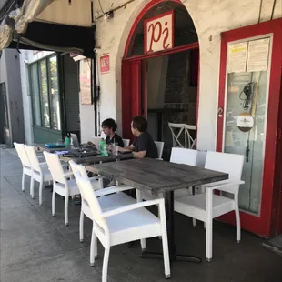 two people sitting at a table outside a restaurant