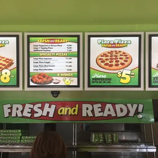 a woman standing in front of a pizza counter