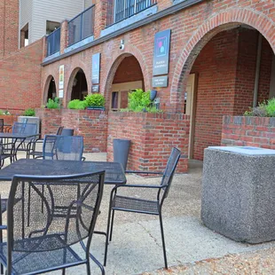 Photo of the outside of Piazza Discepoli. Patio tables and chairs and plants are available for customers.