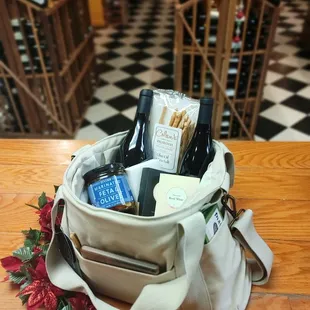 A gift bag idea, wine, breadsticks, and olives in a ivory wine cooler bag.