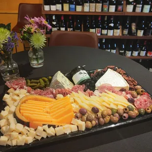 A large custom charcuterie board with a selection of cheeses, meats, jams, fruit, nuts, and pickled items.