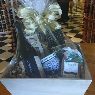 A shrink-wrapped gift box filled with wine, chocolate-covered pretzels, Amaro cherries, Bequet caramels.
