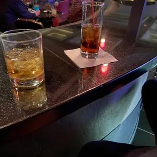 two glasses of alcohol on a bar