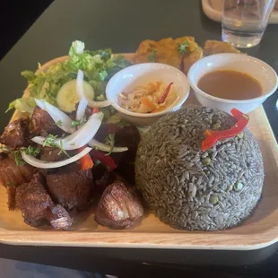 Fried pork, black rice, salad and fried plantains.