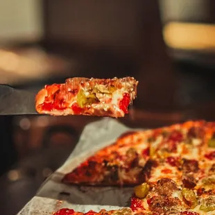 a slice of pizza being taken out of the oven