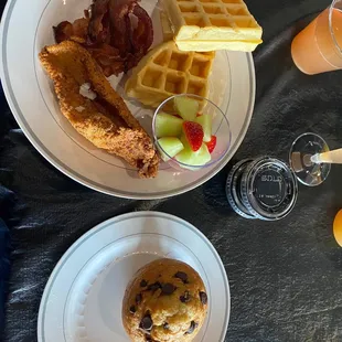 a breakfast of waffles, bacon, and fruit