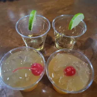 four glasses of alcohol with a cherry and lime garnish