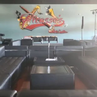 a room with black leather couches and a painting on the wall