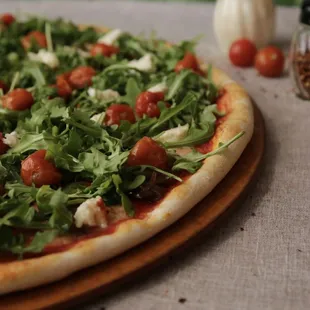 a pizza with tomatoes and arugula