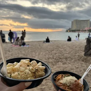 a person holding a bowl of food on the beach