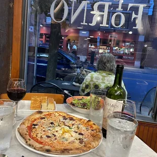 a table with a pizza and a glass of wine