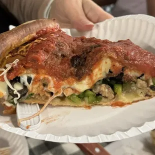 Deep dish pizza with sausage, mushrooms, olives, spinach, tomatoes and peppers