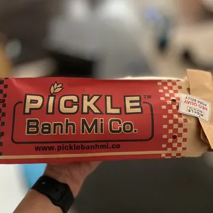 a hand holding a bag of pickle