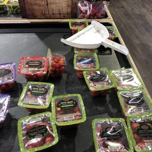 Dirty dustpan on top of produce while three employees were in produce trying to figure out where to put a bunch of watermelon balloons
