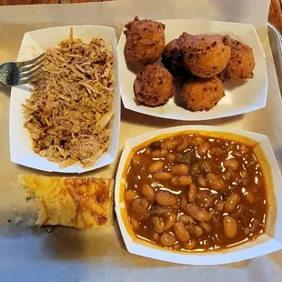 BBQ plate with hush puppies, bakes beans and a piece of corn bread.