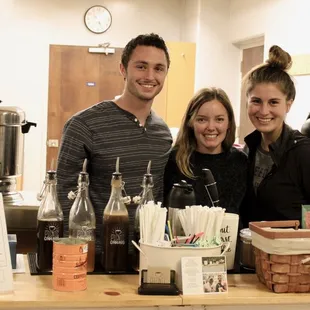 three people standing behind a counter